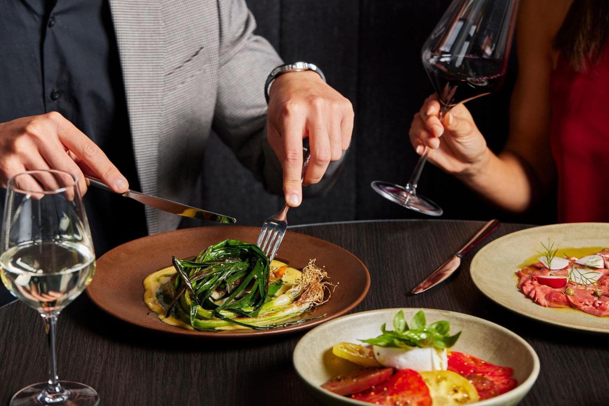 Melbourne Marriott Hotel Docklands Exteriér fotografie A man using a knife and fork to cut into a meal
